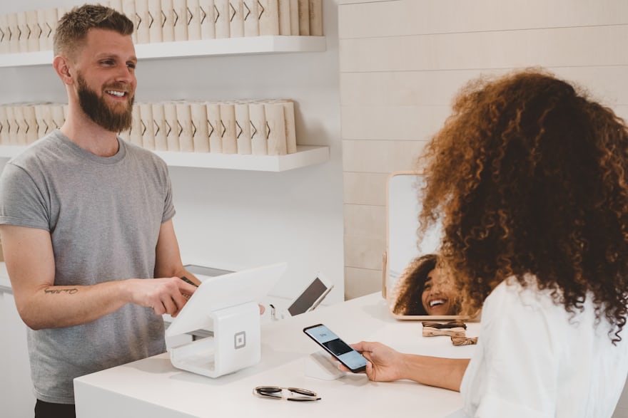 Comerciante atendiendo con un terminal digital mientras la clienta paga con el móvil